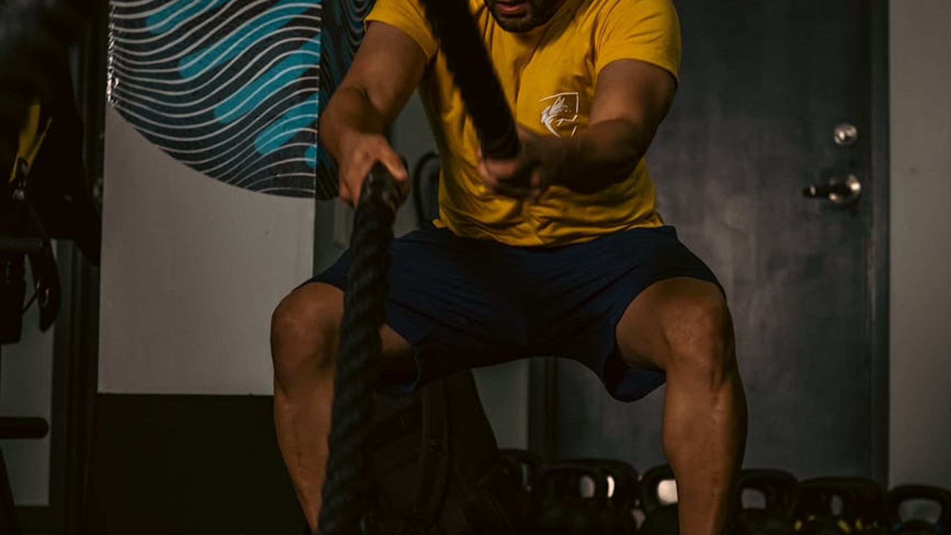 Determined man performing strength training in a dark gym